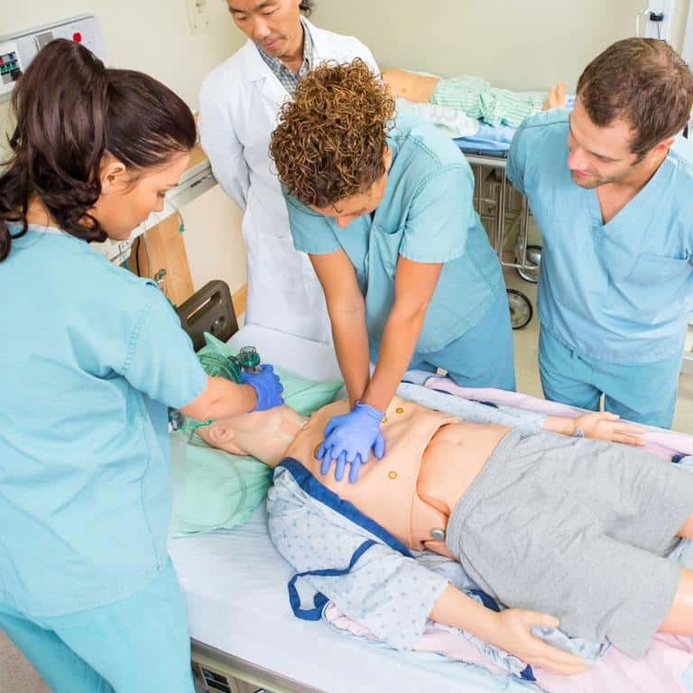 group of nursing students practicing on dummy